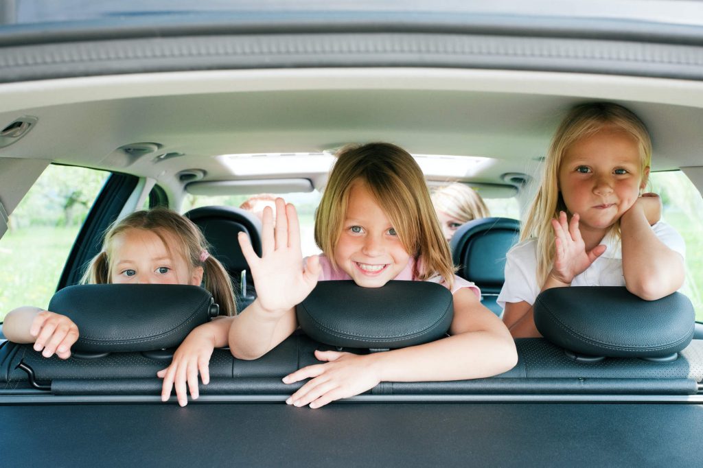 Children in a car, waving.